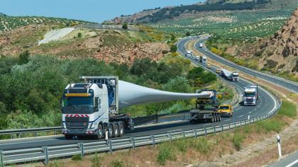 A convoy of trucks transports wind turbine blades.